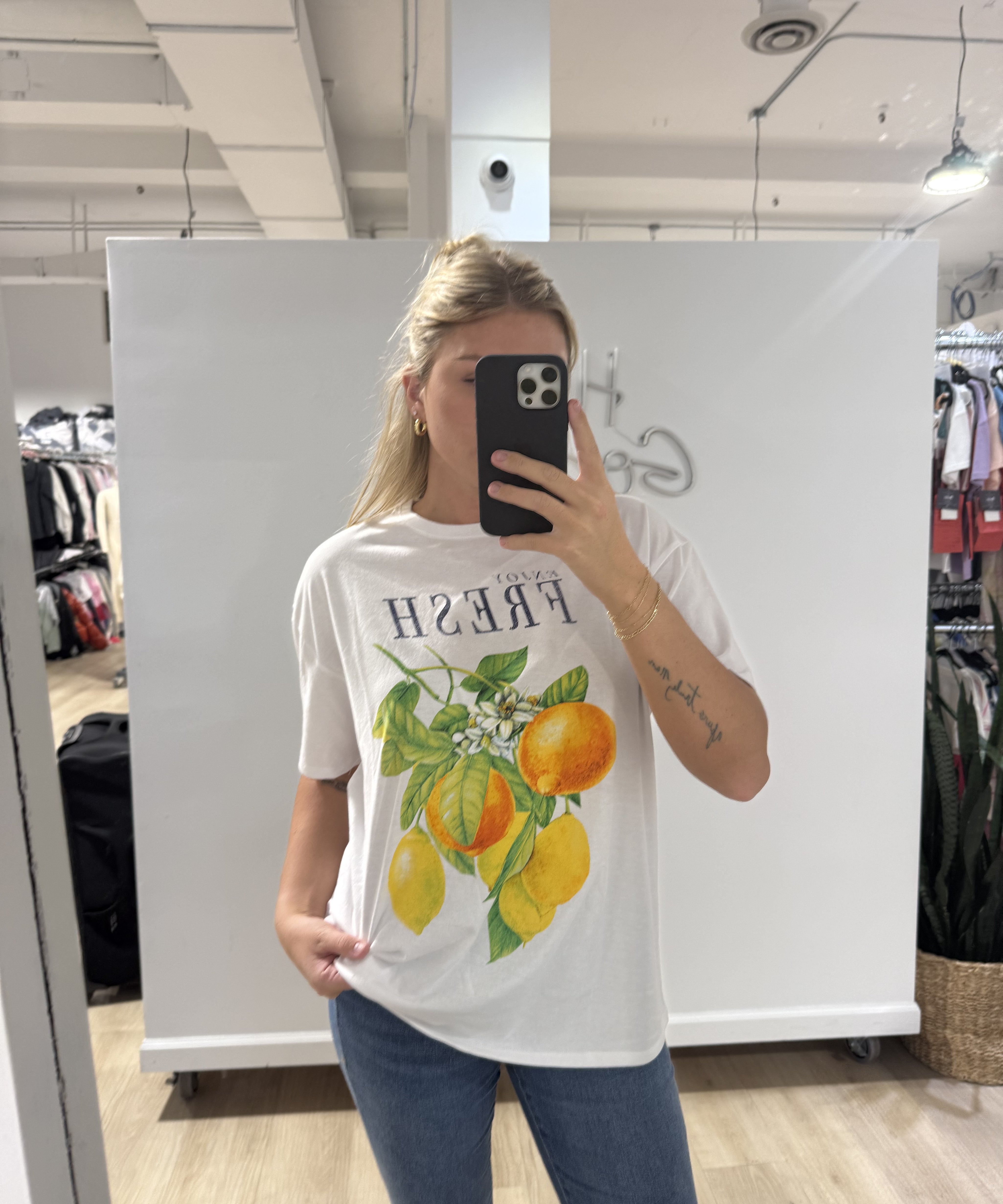 Woman in white tshirt that has black text that says "fresh" and a picture of oranges