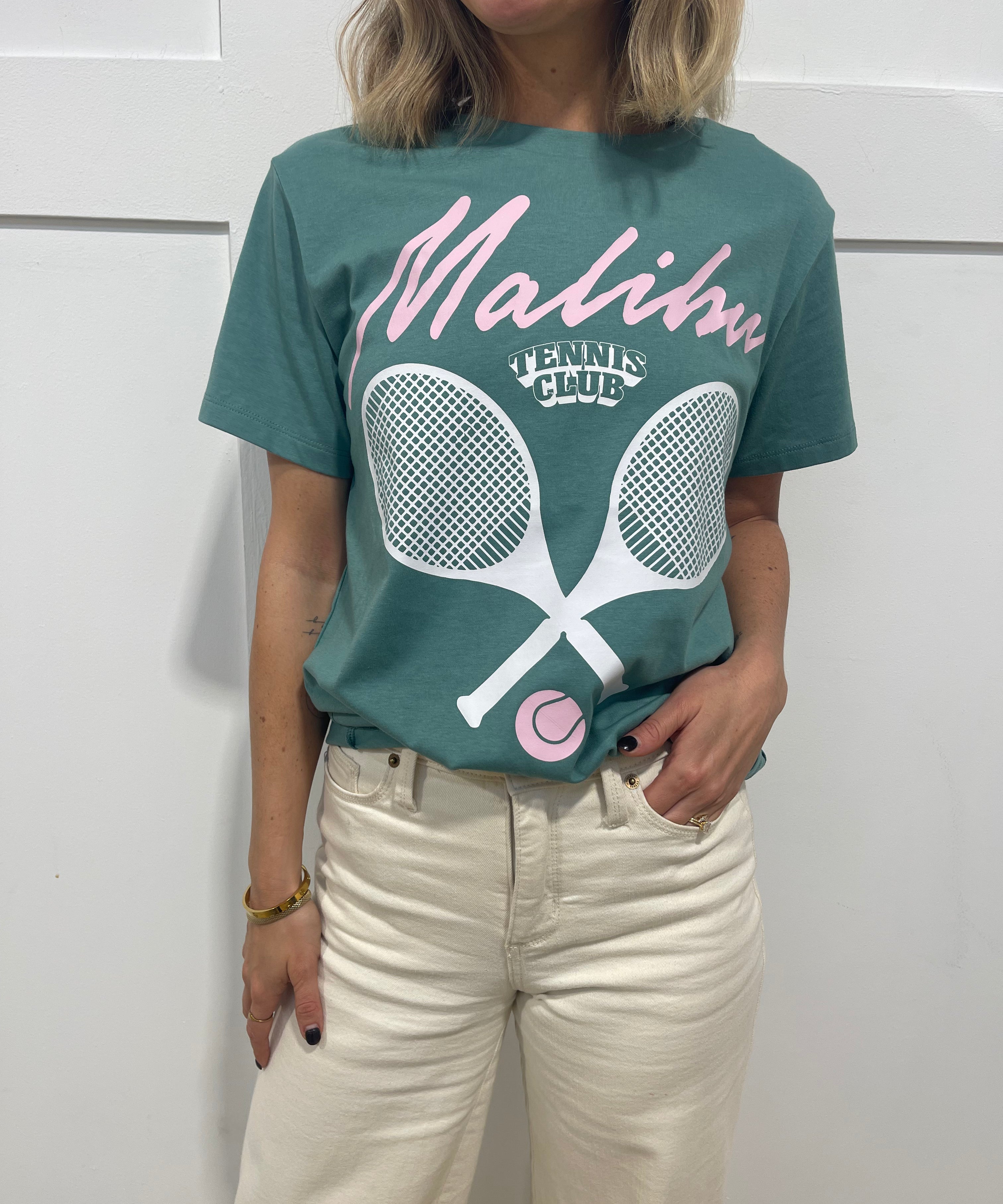 Woman in seafoam pullover that has pink text that says "Malibu"