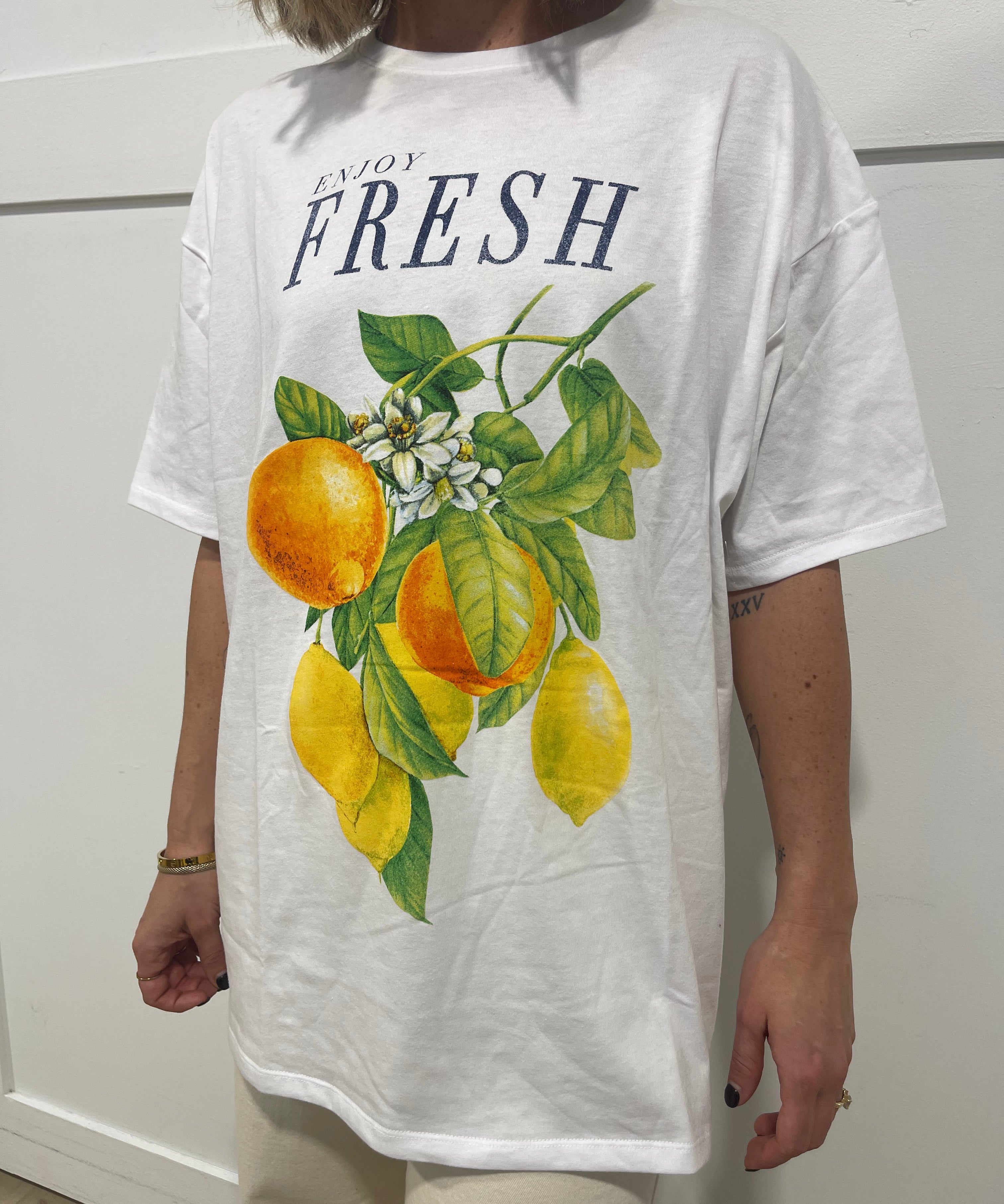 Woman in white tshirt that has black text that says "fresh" and a picture of oranges