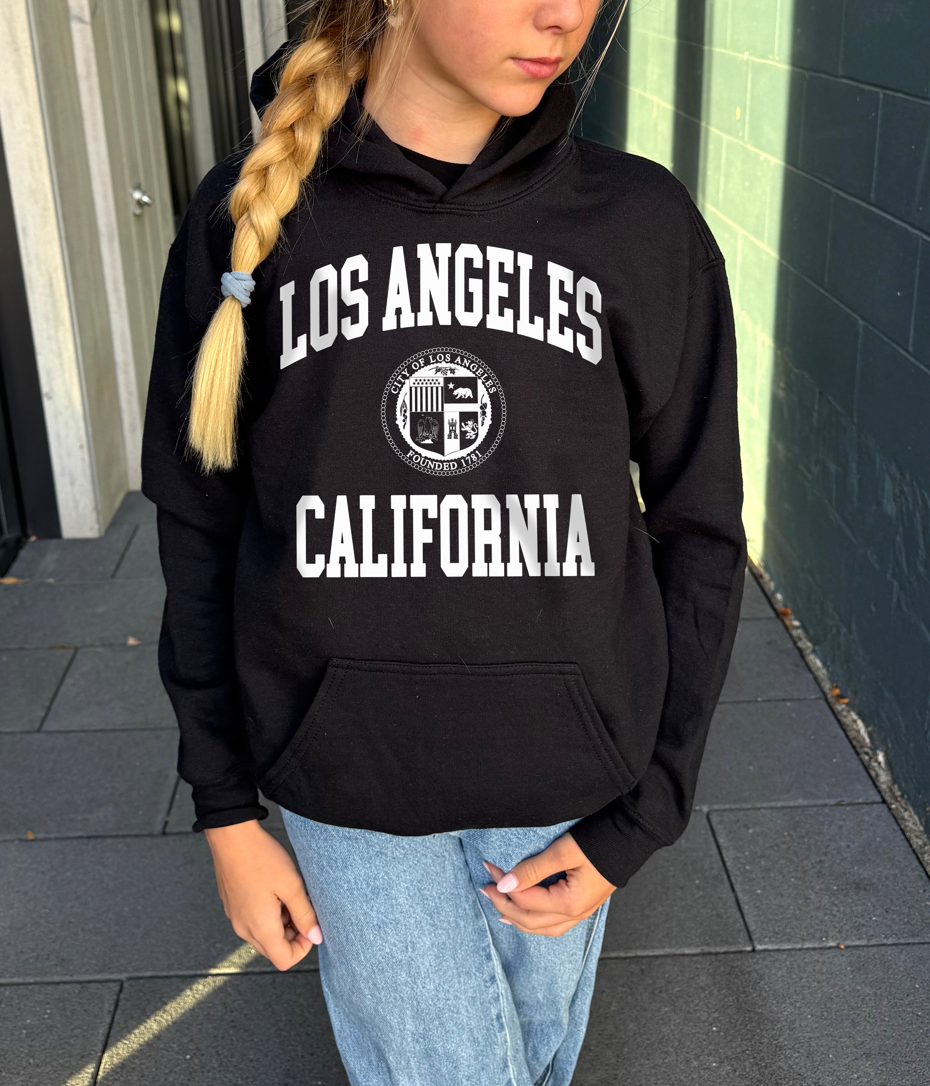 Girl in black hoodie that says "Los Angeles, California" in white text 